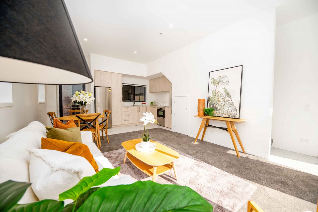 332 Cashel St11 Open-plan living room with a sofa and coffee table, a dining area and a kitchen with light wood cabinetry.